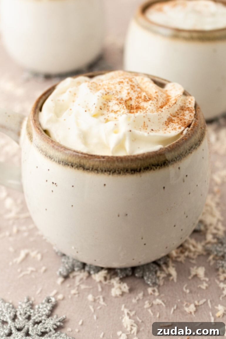 A mug of warm vanilla milk, elegantly topped with whipped cream and sprinkled with cinnamon, beside a plate of delicious Christmas cookies, ready for dunking.