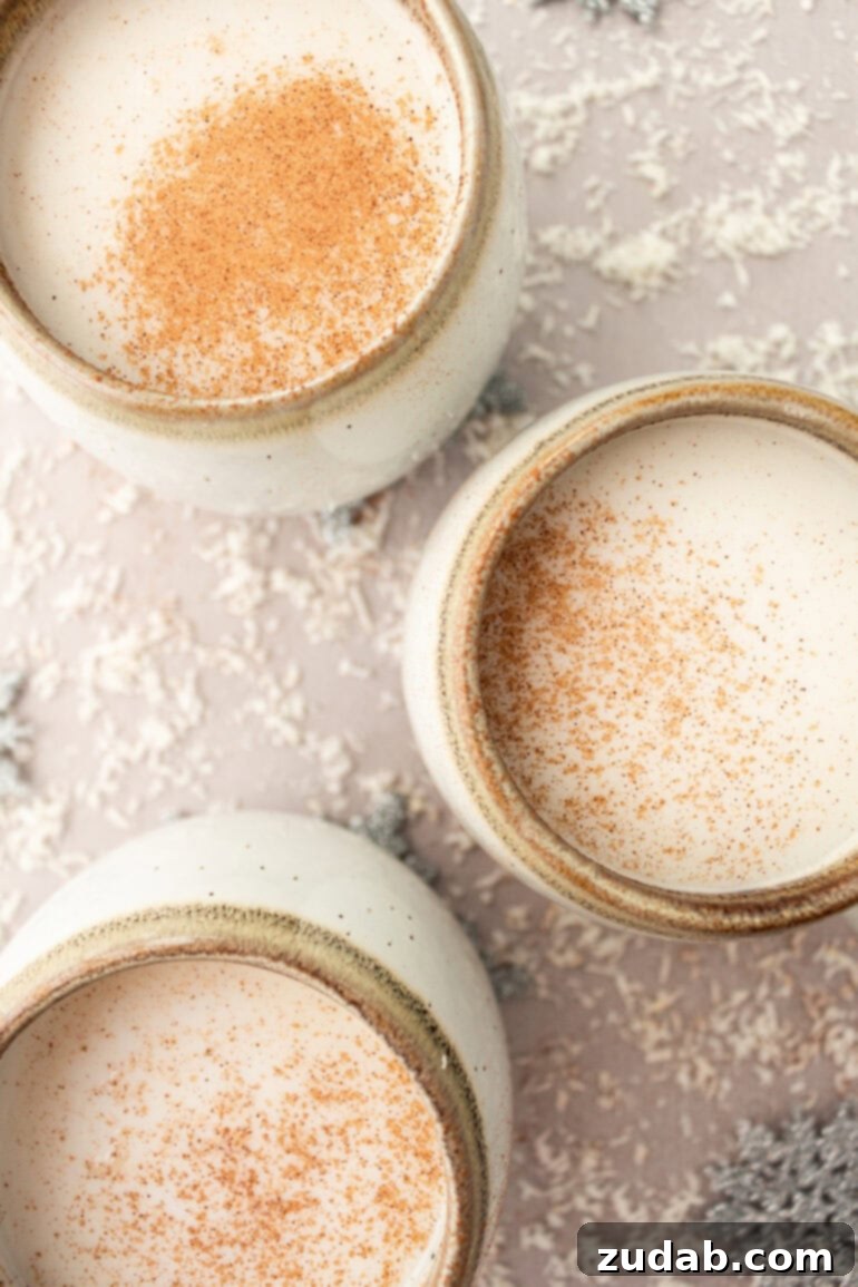 A beautiful arrangement of several mugs filled with warm vanilla milk, each topped with a delicate sprinkle of cinnamon, exuding festive charm.