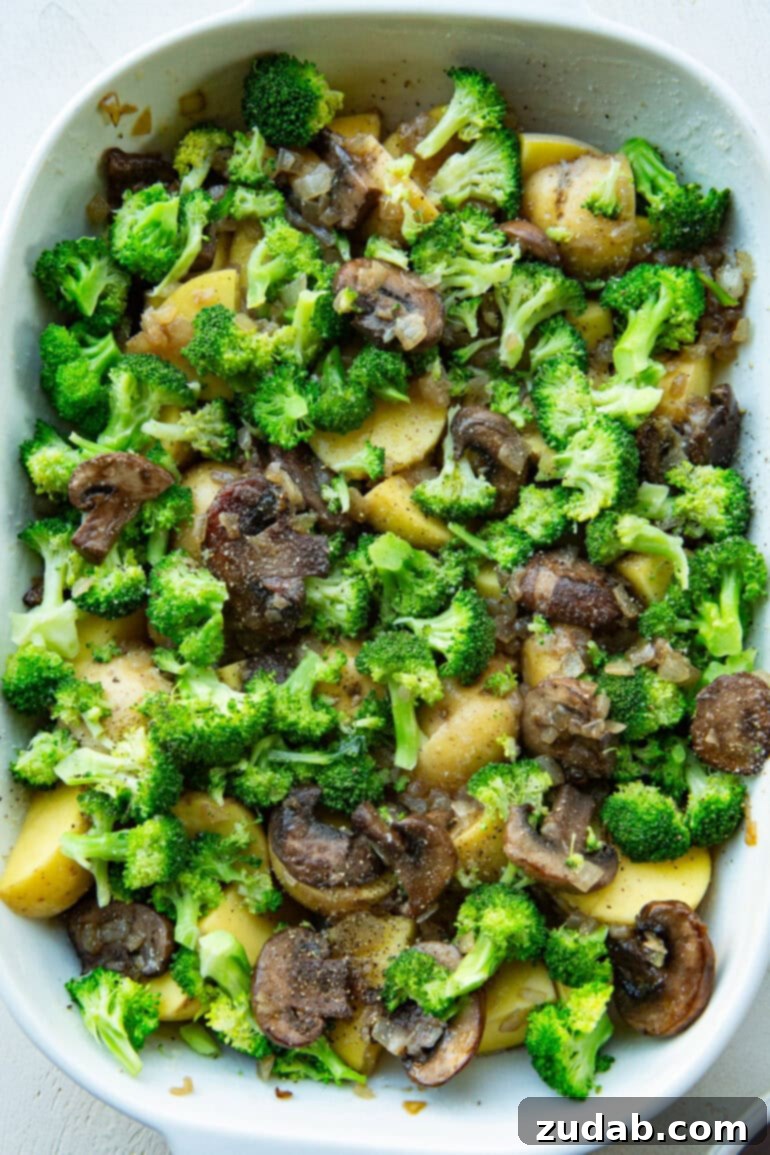 Classic Cheesy Ham, Potato & Broccoli Bake 8 The layering process of the casserole, showing sautéed onions and mushrooms spread over potatoes
