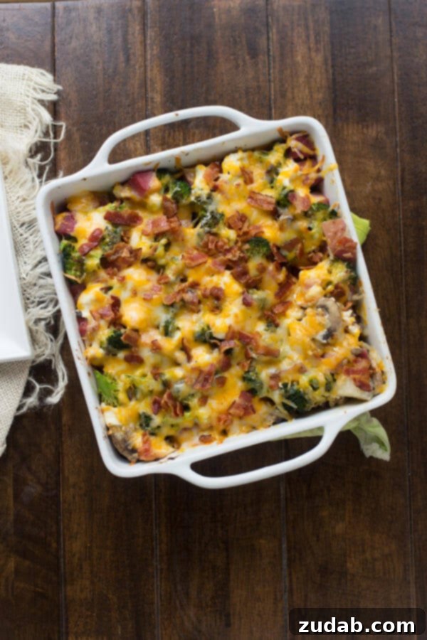 Comforting Ham and Potato Casserole Ready to Enjoy Individual serving of cheesy ham and potato casserole on a white plate with a fork, showing melted cheese and ham pieces.