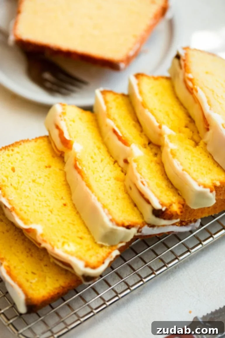Zesty Lemon Glaze Loaf 3 a photo of a loaf of lemon pound cake cut into thin slices sitting on a wire cooling rack