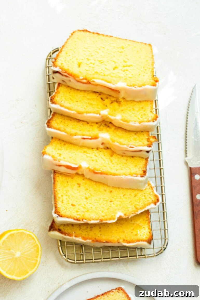 Zesty Lemon Glaze Loaf 5 a photo of lemon pound cake sliced into thin slices laying on each other sitting on a wire cooling rack with a knife sitting next to it