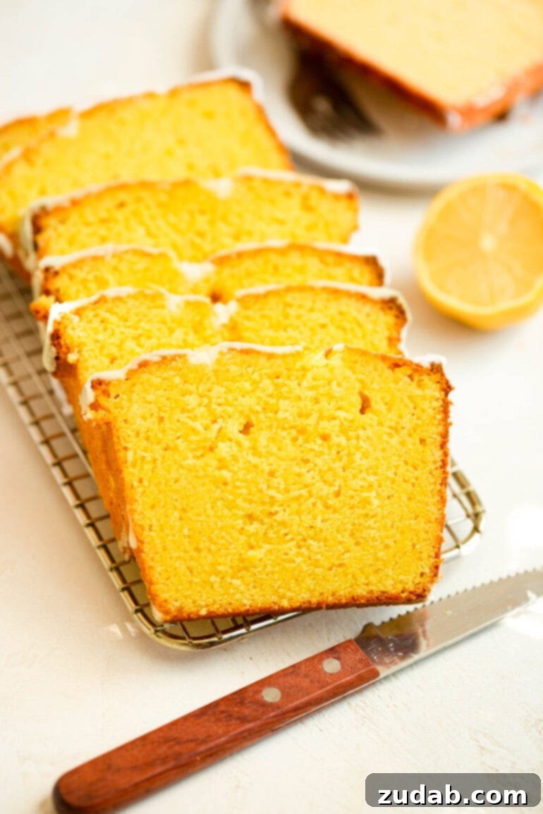 Zesty Lemon Glaze Loaf 7 a photo of lemon loaf cake cut into thin slices laying on each other on a wire cooling rack