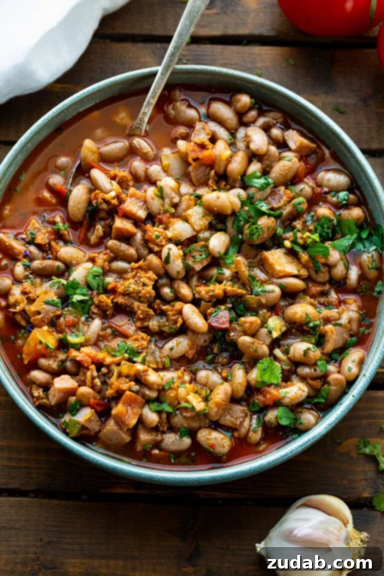 Classic Charro Beans Recipe 12 A large, rustic bowl of seasoned charro beans, generously garnished with freshly chopped cilantro, ready to be enjoyed as a hearty and flavorful Mexican dish.