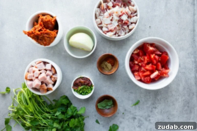 Classic Charro Beans Recipe 5 All the fresh ingredients for charro beans are laid out in small, colorful bowls: diced onions, sliced Roma tomatoes, minced jalapeños, and a selection of seasonings, showcasing the recipe's vibrant components.