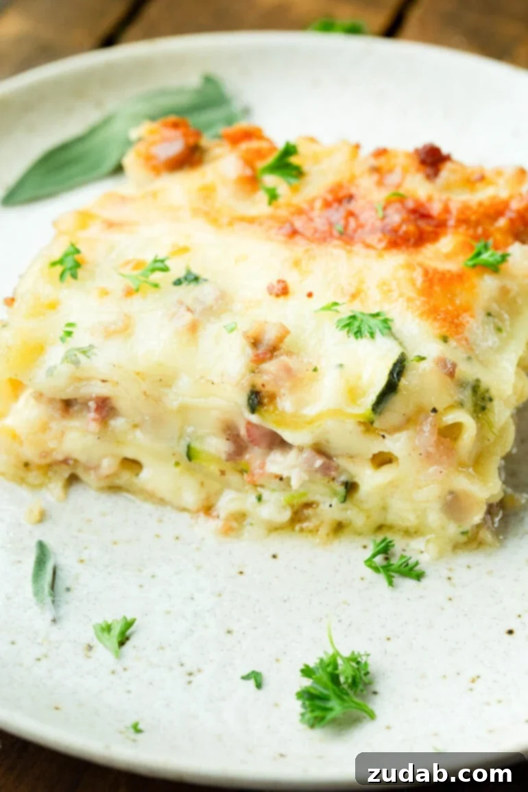 Creamy Vegetable Lasagna with Crispy Pancetta 3 A close-up photo of a serving of golden-baked pancetta vegetable lasagna with white sauce, resting on a pristine white dinner plate.
