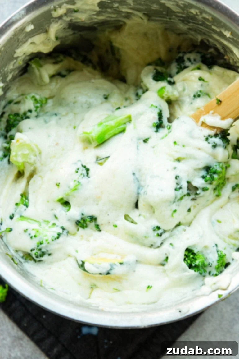 Creamy Vegetable Lasagna with Crispy Pancetta 5 A close-up photo showing cooked broccoli and zucchini being gently stirred into a creamy, luscious white béchamel sauce, ready for layering in a delicious lasagna.