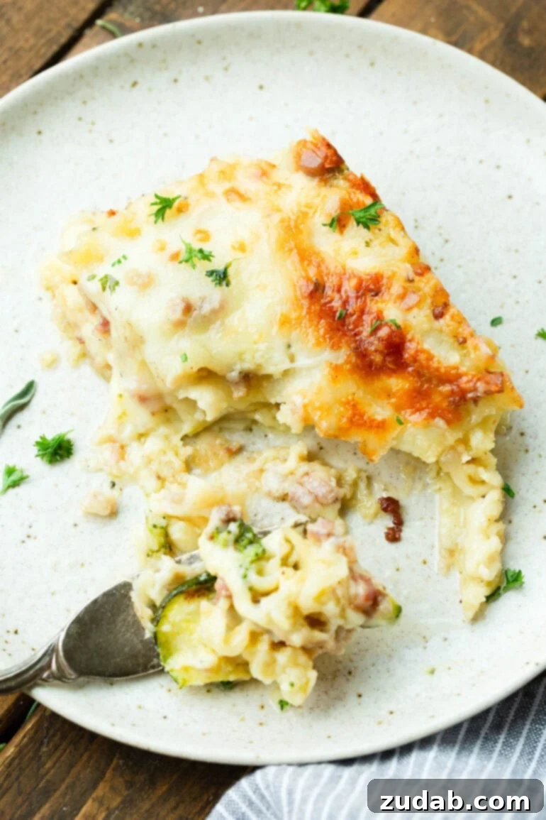 Creamy Vegetable Lasagna with Crispy Pancetta 8 A fork cutting into a serving of creamy pancetta vegetable lasagna with white sauce, showing its tender layers and golden crust.