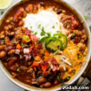 A rustic bowl of Instant Pot chili, richly garnished with shredded cheese, a dollop of sour cream, and a fresh slice of lime, sitting ready to be enjoyed.