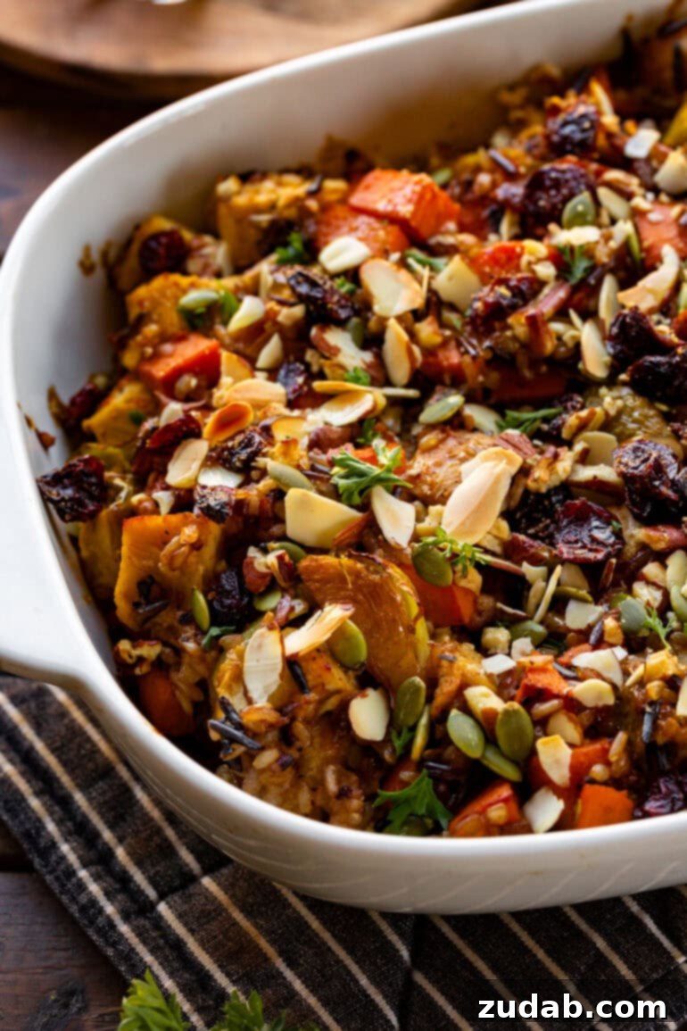 Nourishing Chicken Harvest Bake 7 A white baking dish filled with the rich and creamy Harvest Chicken Casserole, showcasing chicken, sweet potatoes, Brussels sprouts, and a sprinkle of pepitas and red onion, all in a luscious sauce