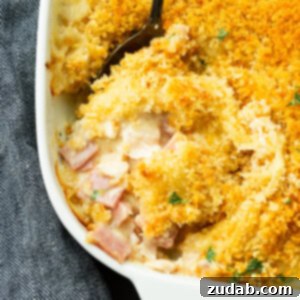 A photo of a chicken cordon bleu casserole with a serving being removed