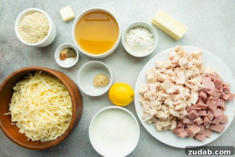 Creamy Chicken Cordon Bleu Casserole 4 A flat lay photo showing all the fresh ingredients for Chicken Cordon Bleu Casserole including raw chopped chicken, Dijon mustard, Swiss cheese, milk, flour, various spices, and chicken broth.