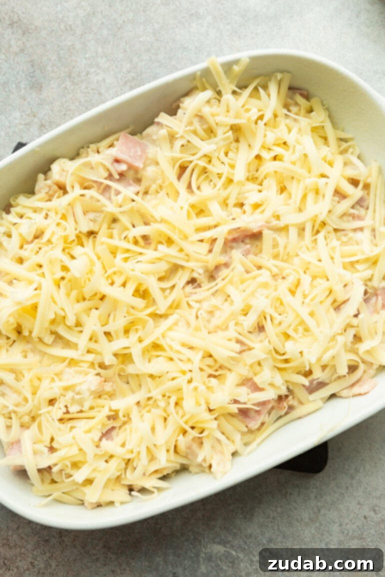 Creamy Chicken Cordon Bleu Casserole 5 A Chicken Cordon Bleu Casserole prepared and topped with shredded Swiss cheese, ready to be placed into the oven for baking.