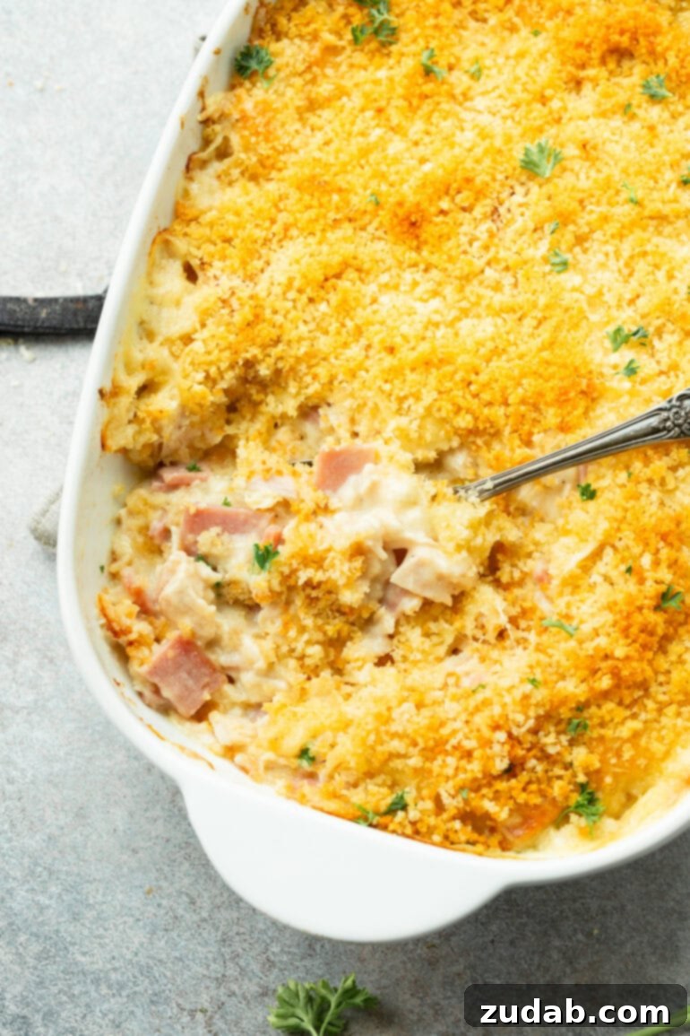 Creamy Chicken Cordon Bleu Casserole 9 A baked Chicken Cordon Bleu Casserole with a serving spoon taking out a portion, showing the melted cheese and creamy sauce.