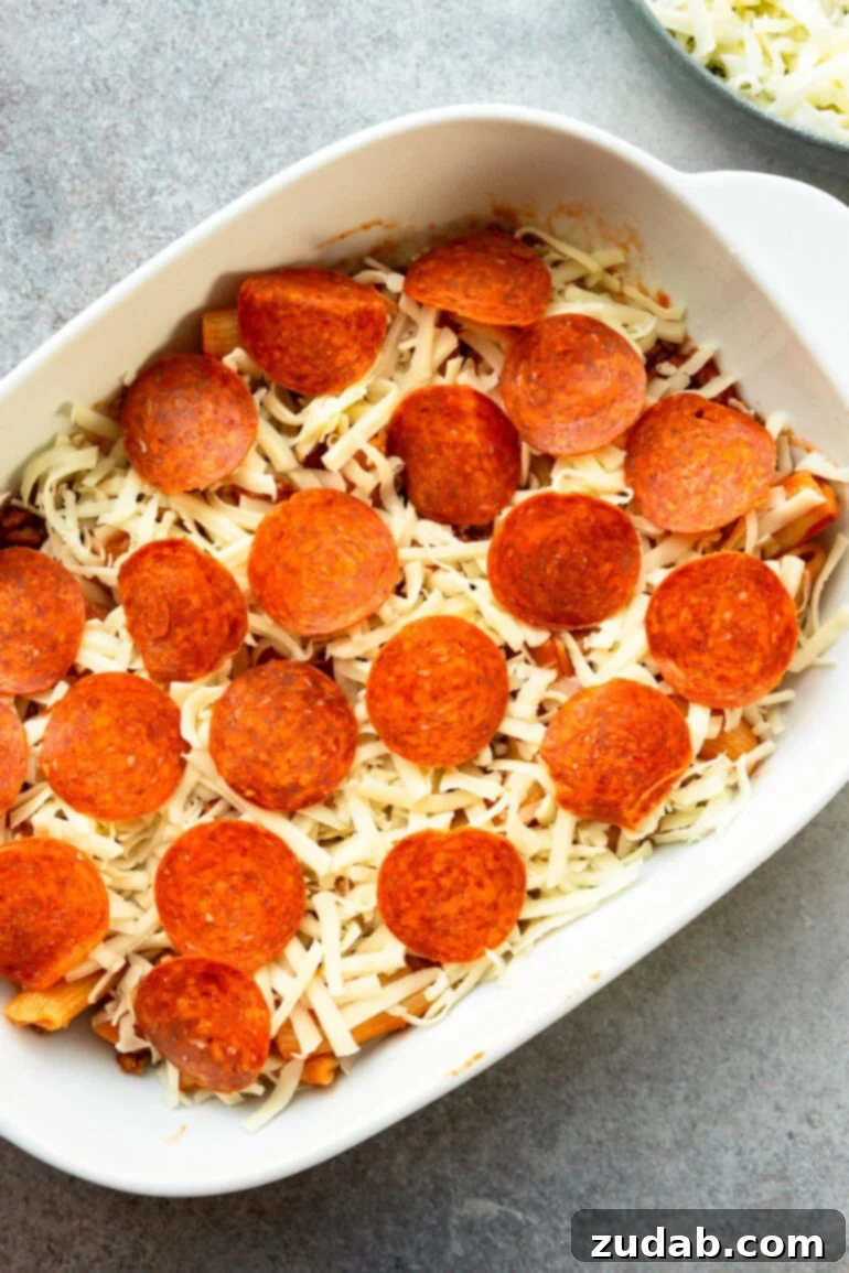 One-Pan Pizza Night Delight 7 a photo of a pizza casserole ready to go in the oven will grated mozzerella on top and pepperonis