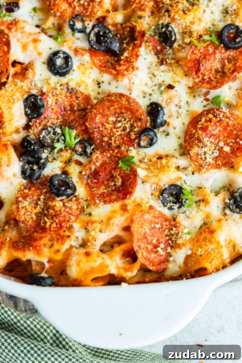 One-Pan Pizza Night Delight 9 a photo of a baked pepperoni pizza casserole sprinkled with sliced olives and fresh herbs