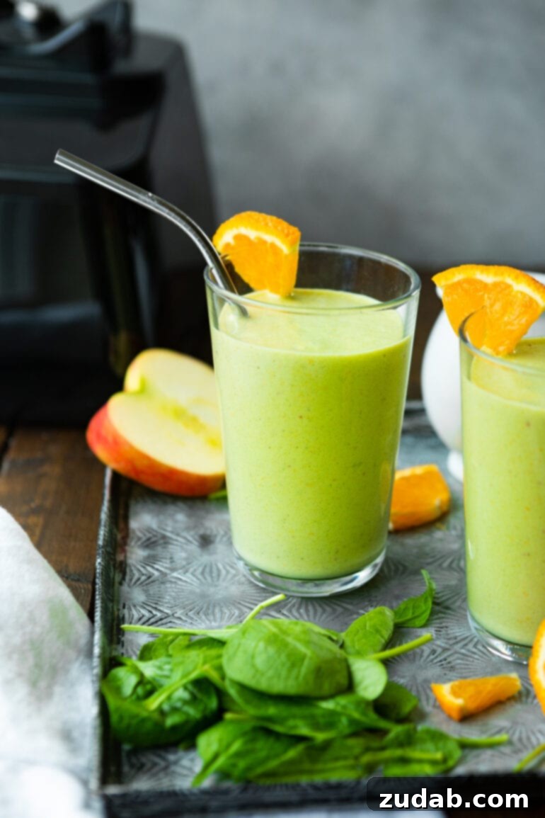 The Ultimate Cold-Busting Green Smoothie 11 A photo of two glasses filled with a bright green smoothie, each garnished with an orange wedge on the rim.
