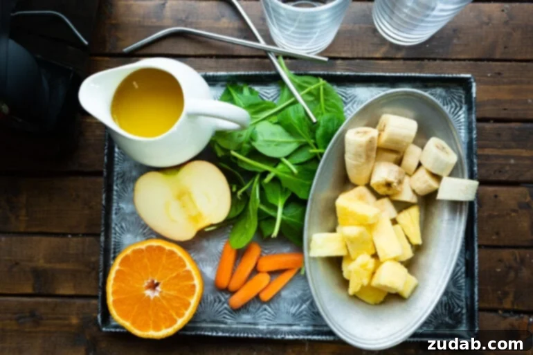The Ultimate Cold-Busting Green Smoothie 4 A photo of a tray displaying all the fresh ingredients for a cold buster green smoothie, including a sliced orange, half an apple, frozen pineapple chunks, frozen banana slices, fresh spinach, orange juice, and baby carrots.