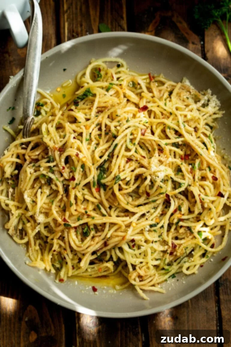 Flavorful Aglio e Olio Made Easy 2 A large plate full of cooked spaghetti pasta tossed with hot oil and fresh herbs, ready to be served
