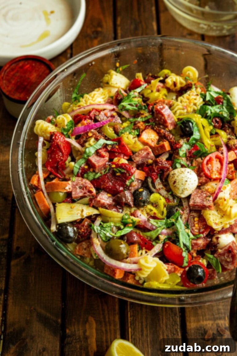 Effortless Antipasto Pasta Salad Recipe 6 A large serving bowl, brimming with antipasto pasta salad, is presented prominently, showcasing the rich blend of pasta, meats, cheeses, and colorful vegetables, all coated in a flavorful dressing, making it ready to be enjoyed as a centerpiece dish.