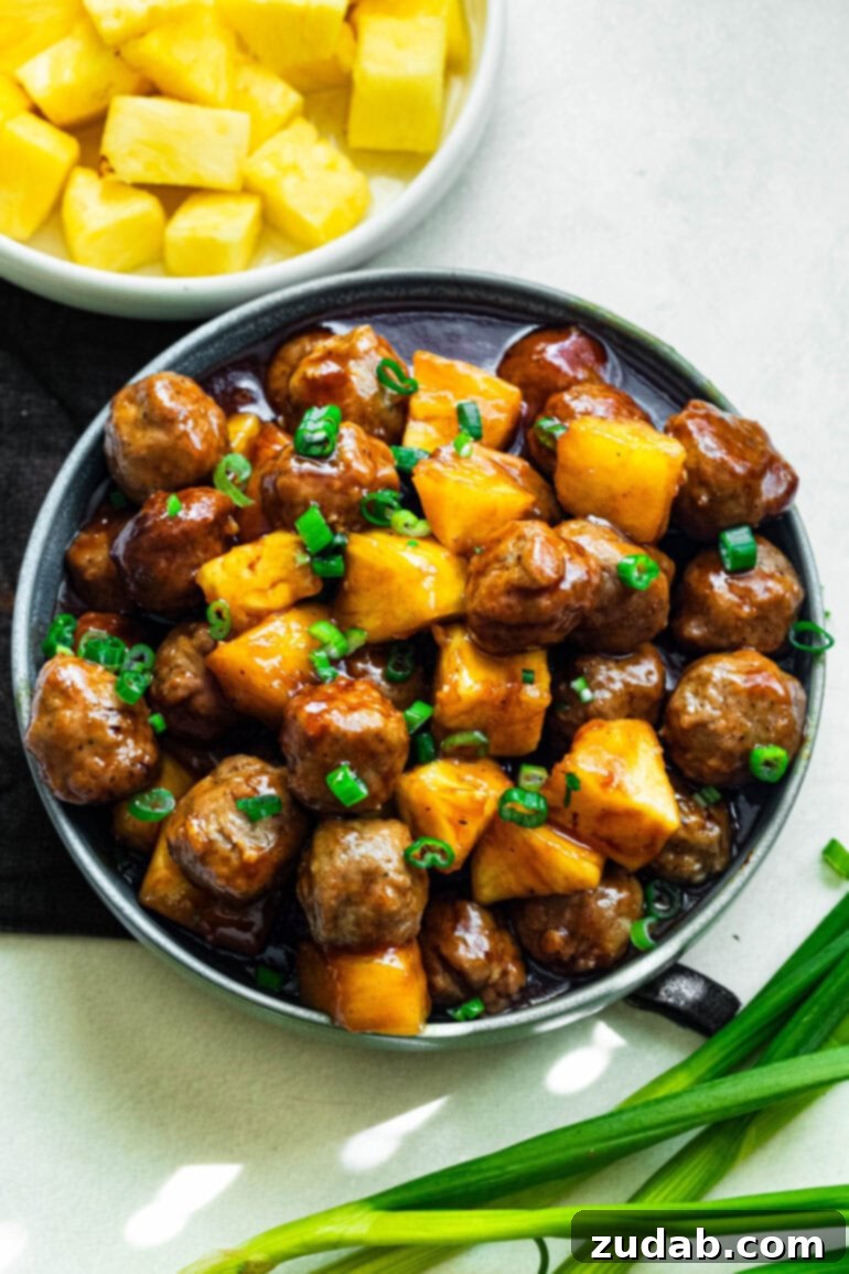 Slow Cooker Island Glazed Meatballs 7 A generously sized serving bowl filled with irresistible saucy Hawaiian meatballs, mixed with succulent pineapple chunks and elegantly topped with finely chopped green onions.