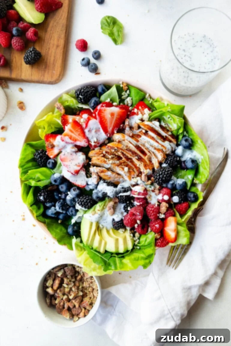 Fresh & Fit Berry Avocado Chicken Salad 3 An overhead shot of a vibrant Berry Avocado Chicken Salad, showcasing sliced chicken breast, fresh mixed berries, creamy avocado, and a generous drizzle of poppyseed dressing.