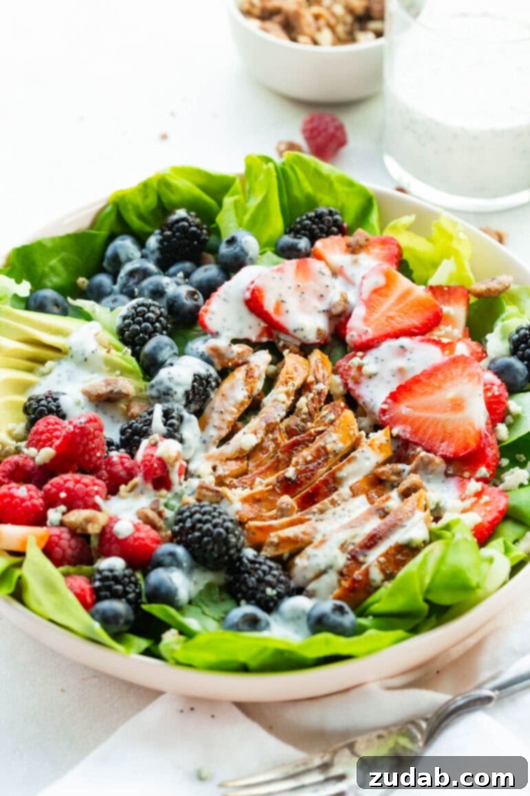 Fresh & Fit Berry Avocado Chicken Salad 5 A large serving bowl of Berry Avocado Chicken Salad, beautifully topped with a generous amount of creamy homemade poppyseed dressing, ready to be enjoyed.