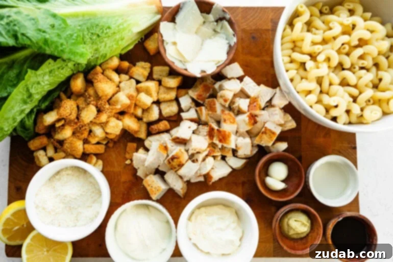 Creamy Chicken Caesar Pasta Salad 3 A vibrant flat lay photo showcasing all the fresh ingredients for a Chicken Caesar Pasta Salad, including pasta, chicken, romaine, and homemade dressing components.