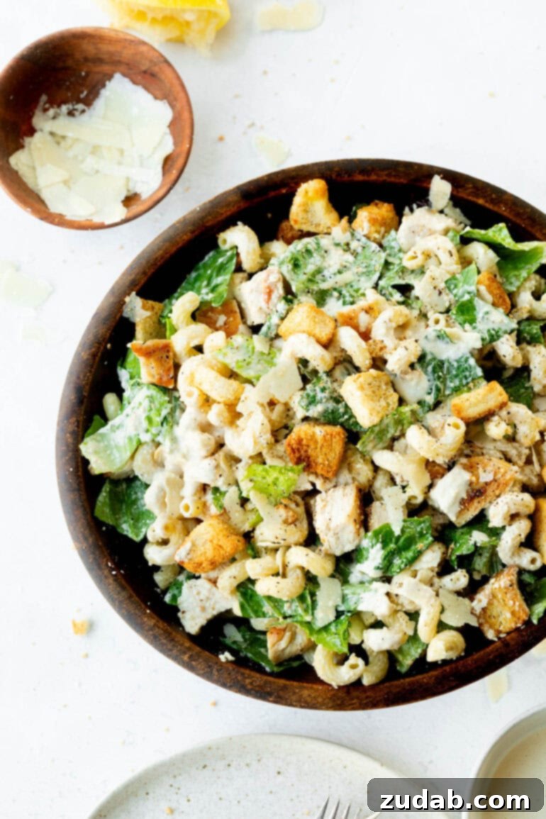 Creamy Chicken Caesar Pasta Salad 4 An inviting overhead shot of a large wooden bowl overflowing with creamy Chicken Caesar Pasta Salad, ready to be served.