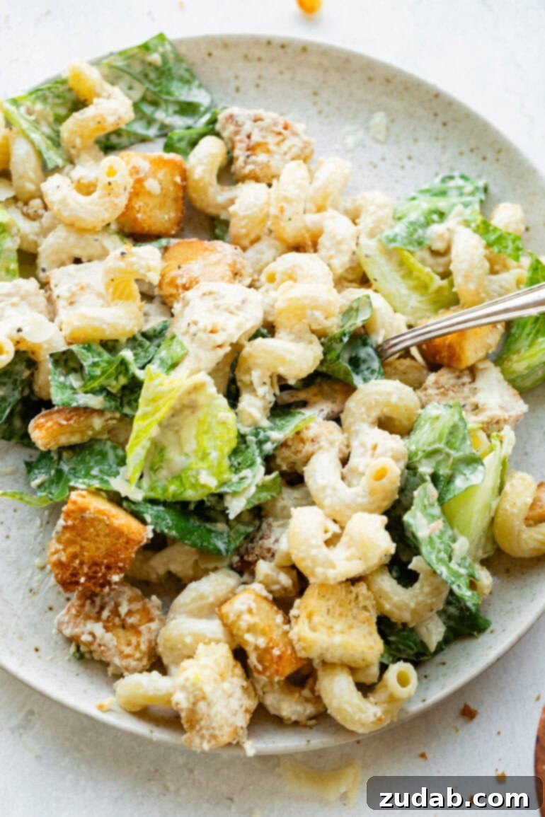 Creamy Chicken Caesar Pasta Salad 5 A perfectly plated serving of creamy Chicken Caesar Pasta Salad on a dinner plate, with a fork ready to dive in.