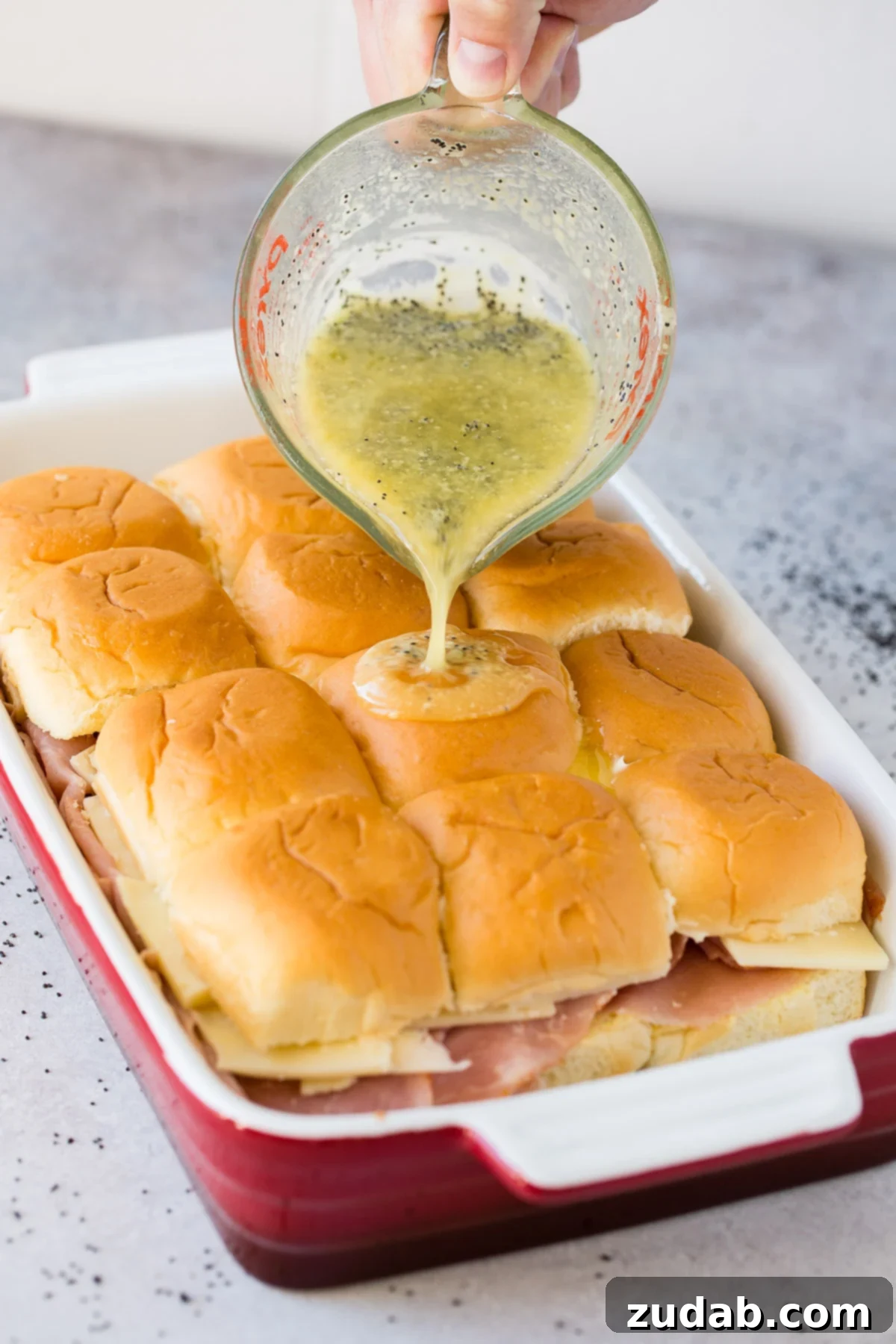 Melty Ham and Cheese Buns 3 Warm and gooey ham and cheese sliders on soft Hawaiian rolls, drizzled with a rich poppy seed dressing.