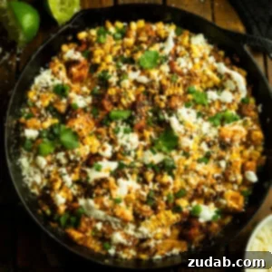 One-Pan Mexican Elote Chicken 13 a photo of a cast iron skillet of cooked chicken chunks mixed with mexican street corn