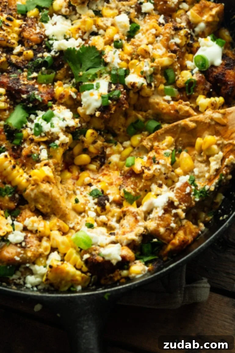 One-Pan Mexican Elote Chicken 3 a photo of a wooden spoon scooping up a serving of mexican street corn chicken