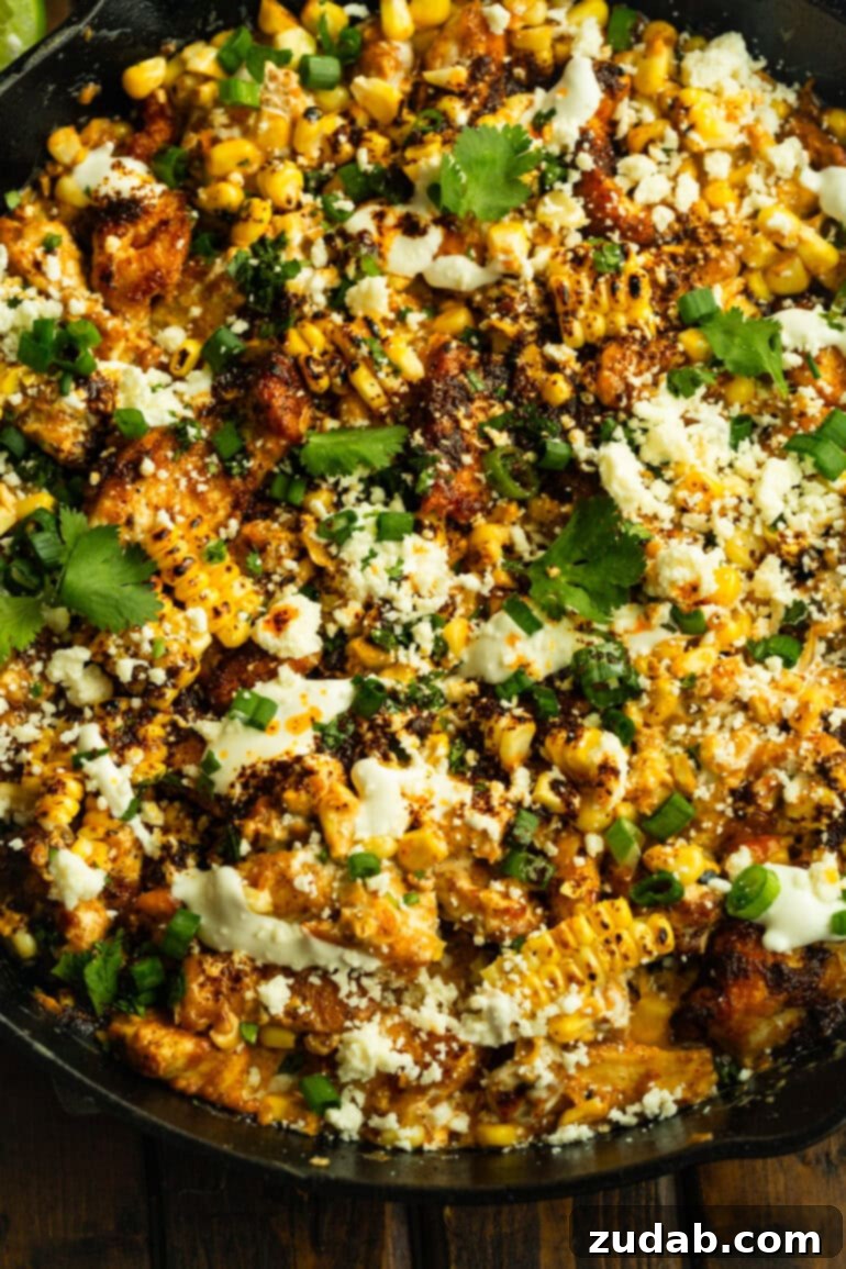 One-Pan Mexican Elote Chicken 10 a photo of a dish of mexican street corn chicken with charred corn kernels, fresh cilantro, cotija cheese and mexican crema