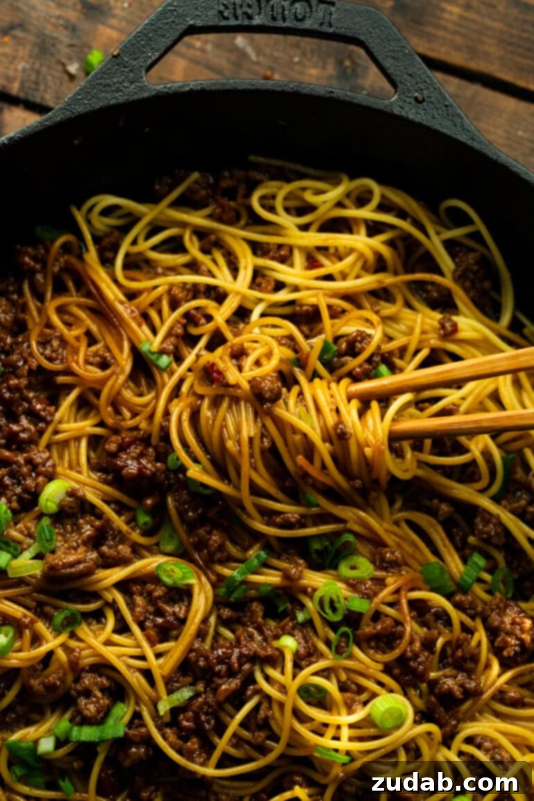 Easy Korean Ground Beef Noodles 10 A dynamic shot of hands using chopsticks to toss flavorful Korean ground beef noodles, capturing the essence of a delicious, freshly mixed meal.