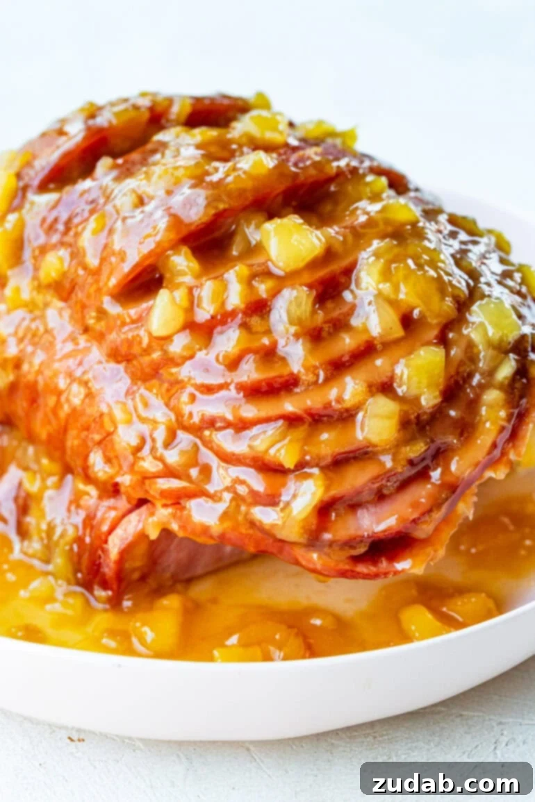 Your New Favorite Slow Cooker Ham 2 a photo of a spiral cut ham topped with a juicy pineapple glaze on a large white serving platter
