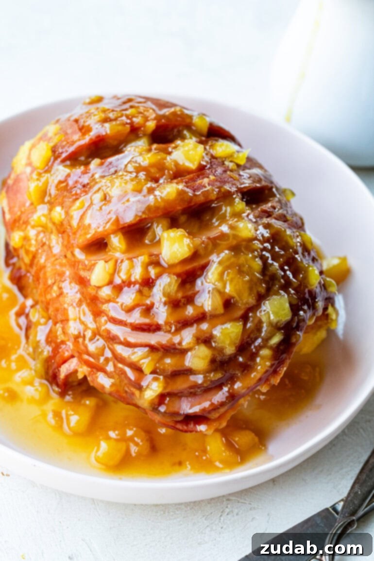 Your New Favorite Slow Cooker Ham 7 a photo of a spiral cut ham sitting on a serving platter topped with a juicy pineapple glaze