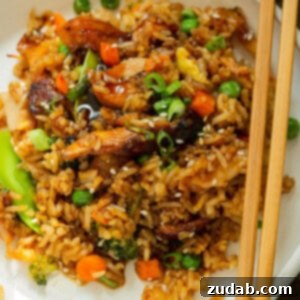 The Best Teriyaki Chicken Casserole 7 A photo of a dinner plate full of a teriyaki chicken casserole including fried rice, large chunks of chicken and assorted vegetables with chopsticks sitting on the side.