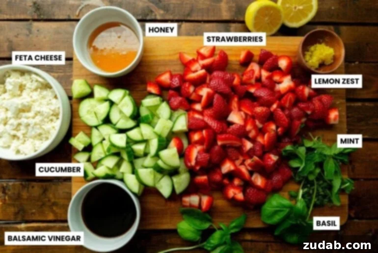 Refreshing Strawberry Feta Salad with Lemon, Cucumber, Basil and Mint 3 A flat lay photograph showcasing all the fresh ingredients needed for the strawberry cucumber feta salad, including basil, mint, lemon, honey, balsamic vinegar, strawberries, cucumbers, and crumbled feta cheese.