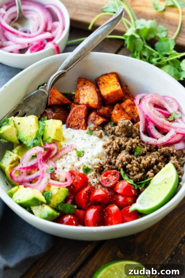 A vibrant high-protein cottage cheese beef and sweet potato bowl, garnished with fresh avocado slices, bright pickled red onions, creamy cottage cheese, and juicy cherry tomatoes.