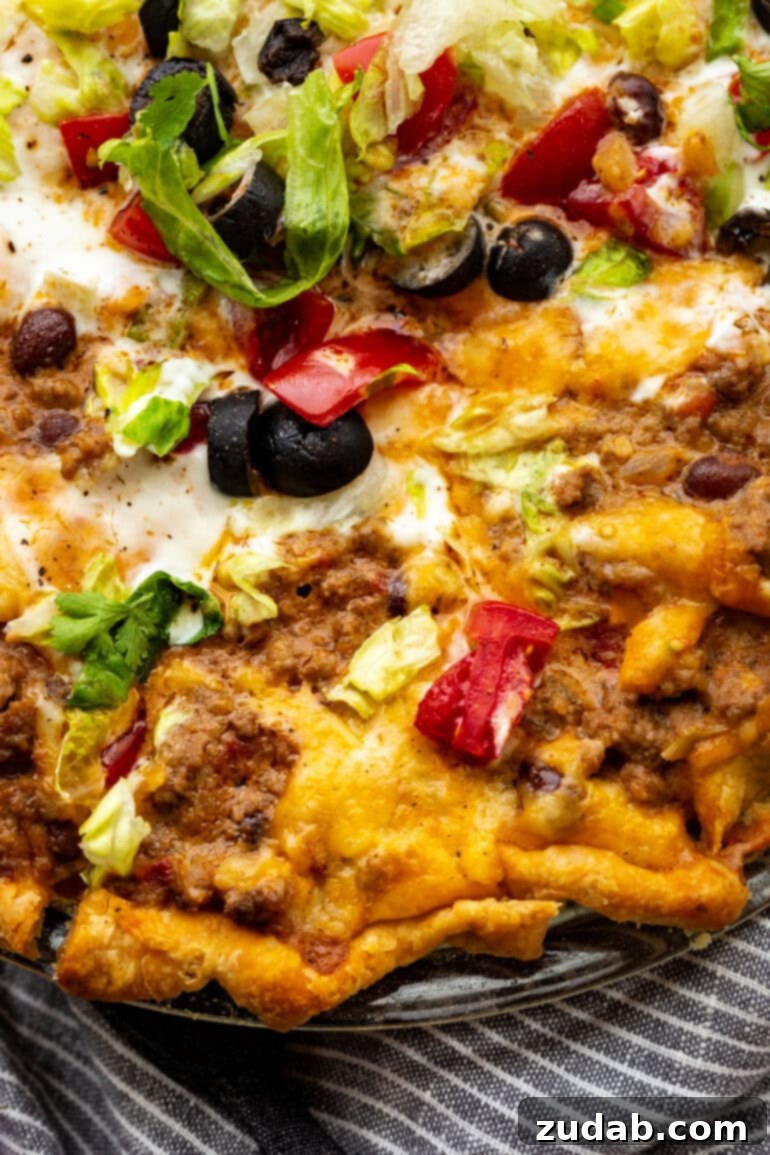 No-Fuss Weeknight Taco Pie 4 A tempting slice of cheesy taco pie being carefully lifted from a full pie plate, revealing its layered filling and golden crust.