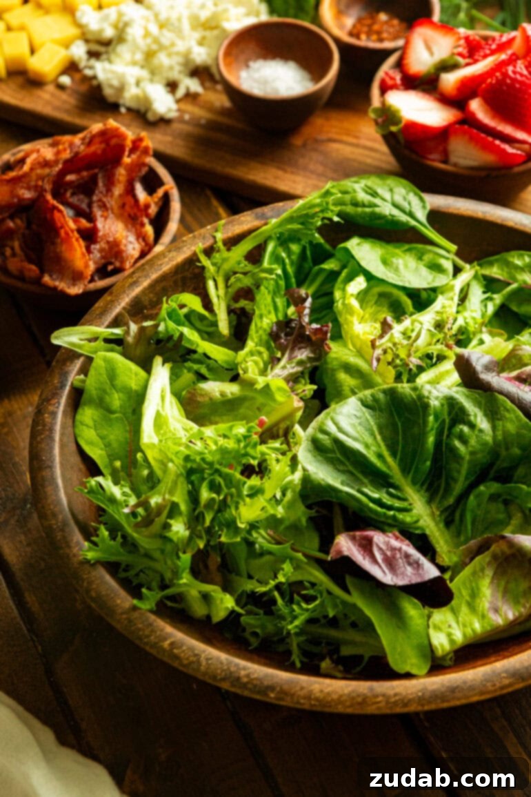 Summer Grilled Chicken Salad with Creamy Basil Dressing 5 a photo of a large wooden serving bowl full of mixed greens with a small bowl of cooked bacon in the background