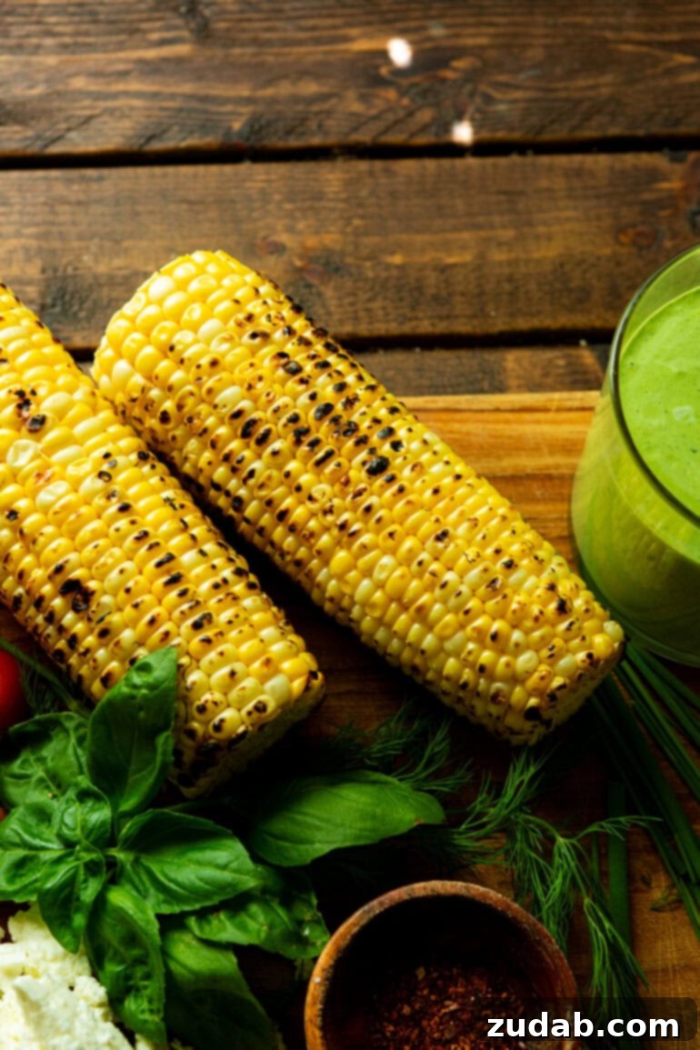 Summer Grilled Chicken Salad with Creamy Basil Dressing 6 a photo of two charred corn on the cobs with a glass of creamy basil dressing next to it