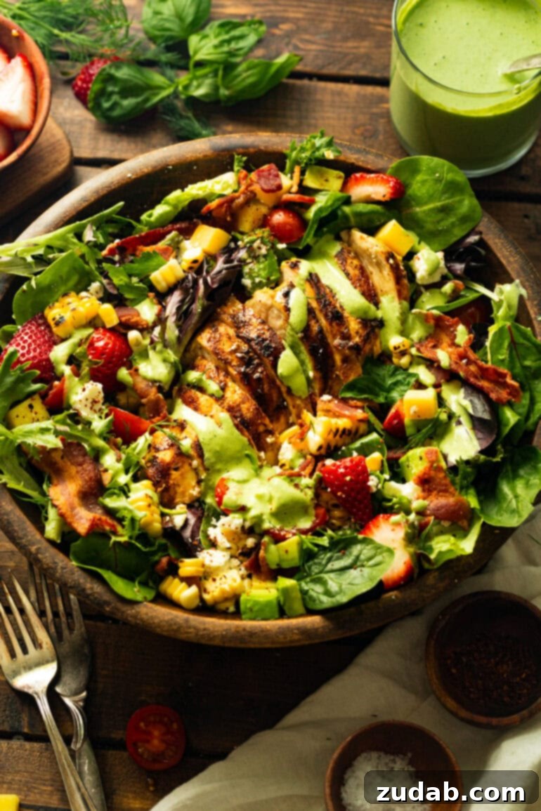 Summer Grilled Chicken Salad with Creamy Basil Dressing 8 a photo of sliced grilled chicken breasts on top of mixed greens and drizzled with creamy basil dressing