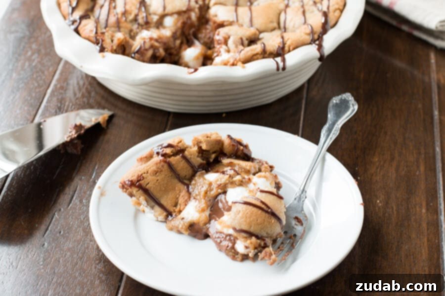 Reese's Peanut Butter Marshmallow Cookie Pie Serving A serving of Reese's Peanut Butter Marshmallow Cookie Pie on a white plate with a fork.