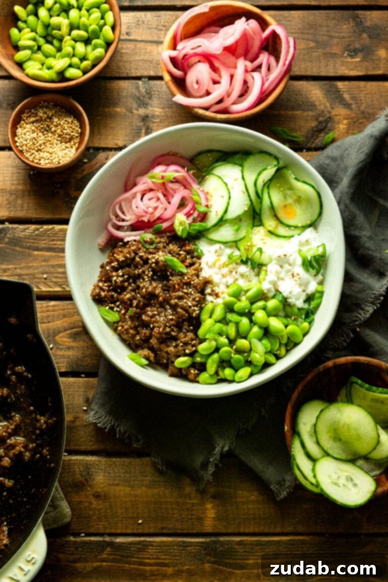 Easy High Protein Korean Beef Bowl with Cottage Cheese 4 a photo of a ground beef cottage cheese bowl with edamame beans, cucumber slices and picked red onions in a large white bowl