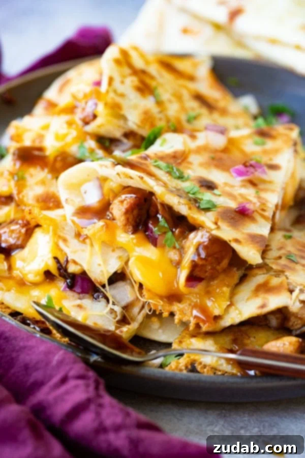 A photo of a slice of teriyaki chicken quesadilla garnished with minced red onion and chopped fresh cilantro.