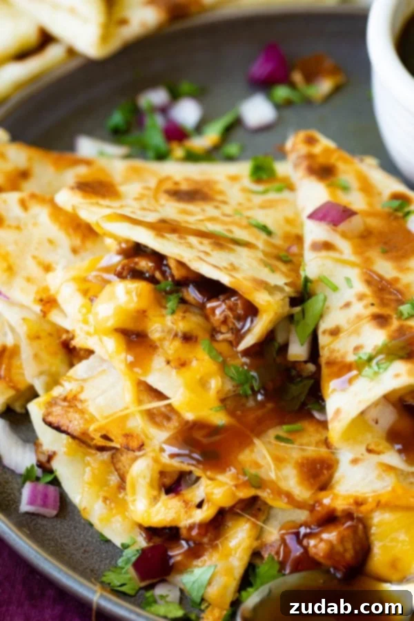 A photo of a slice of teriyaki chicken quesadilla garnished with minced red onion and chopped fresh cilantro.