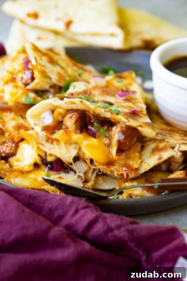 A photo of a slice of teriyaki chicken quesadilla garnished with minced red onion and chopped fresh cilantro.