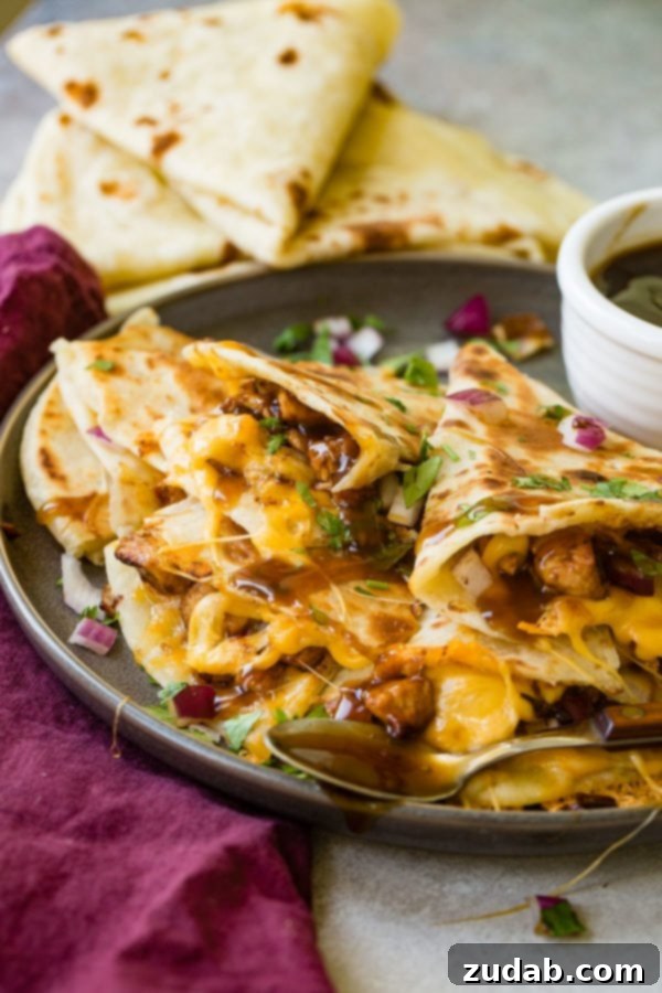 A photo of several slices of teriyaki chicken quesadilla garnished with minced red onion and chopped fresh cilantro.